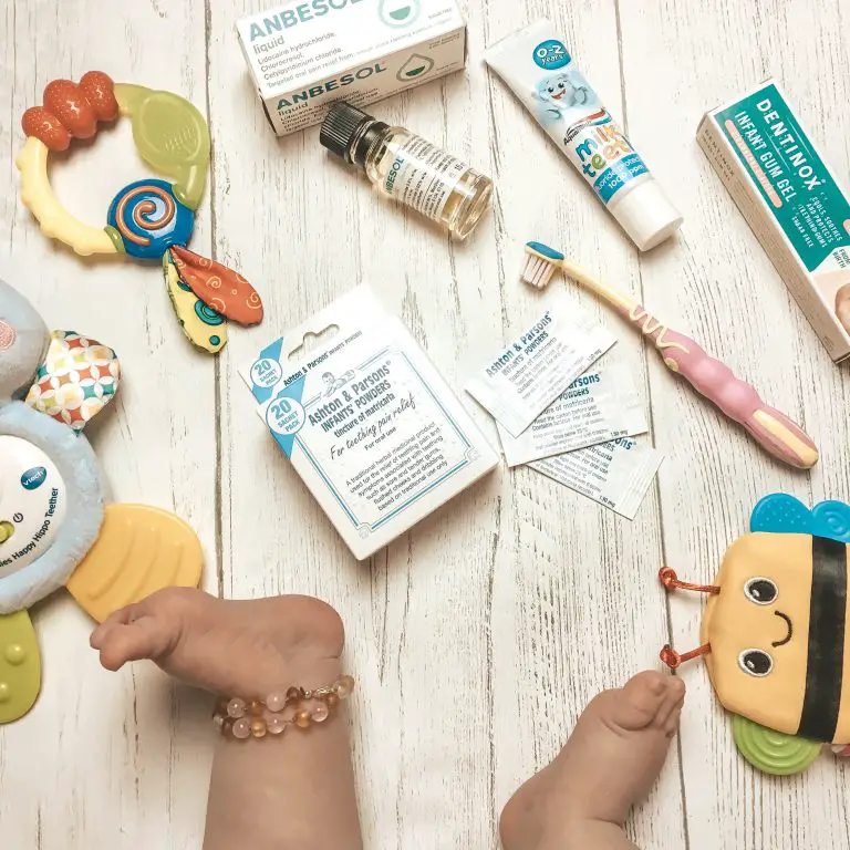 baby feet with an amber anklet surrounded by teething toys and products